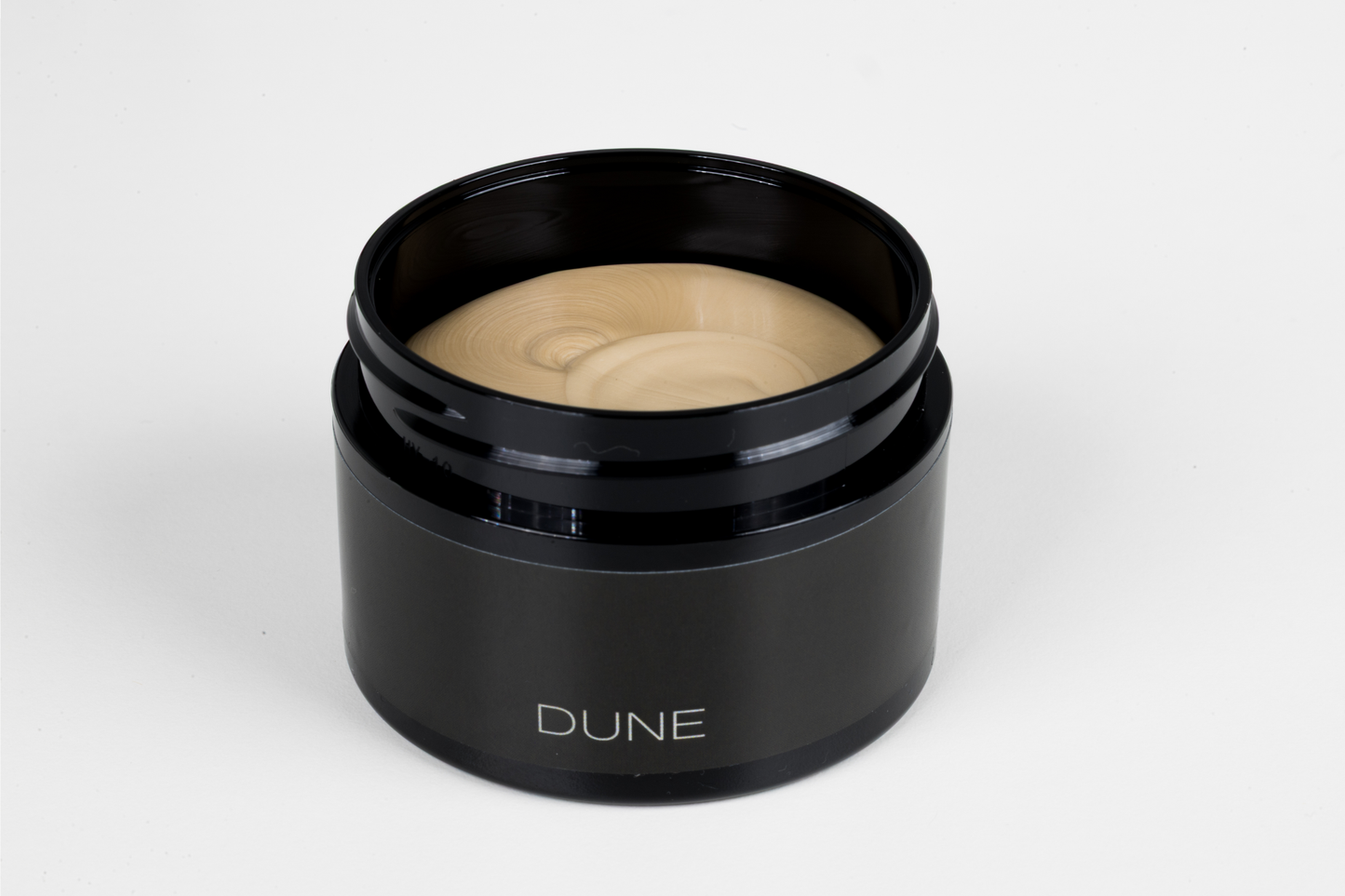 Black jar of cream with 'DUNE' branding on a white background
