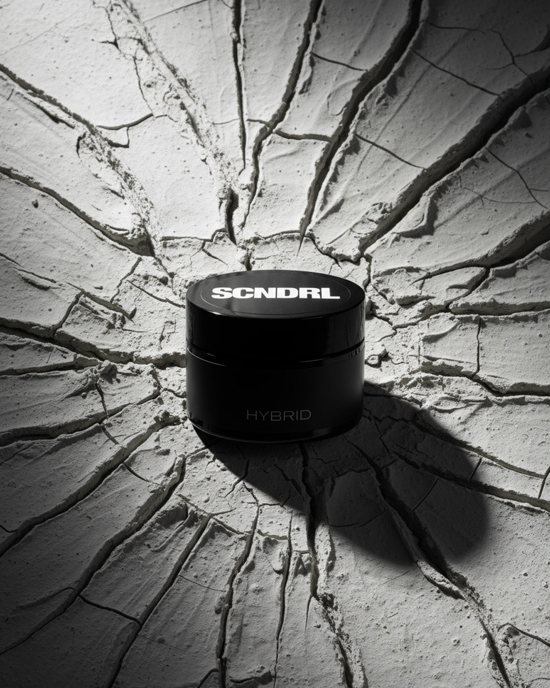 Black container with 'SCNDRL' branding on a cracked concrete surface